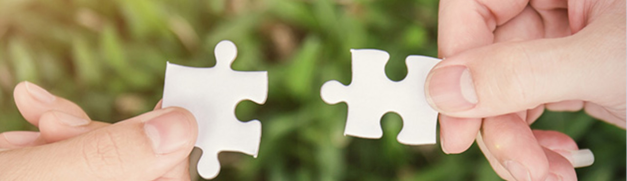twee puzzelstukjes worden bij elkaar gebracht door twee handen