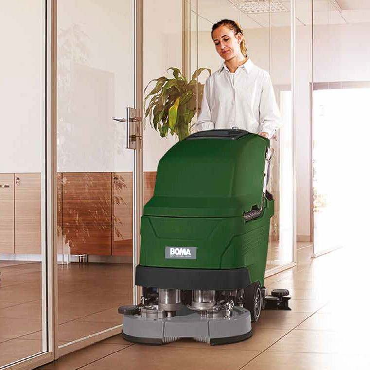 Schoonmaakster loopt achter een schrobzuigmachine en maakt de gangen schoon